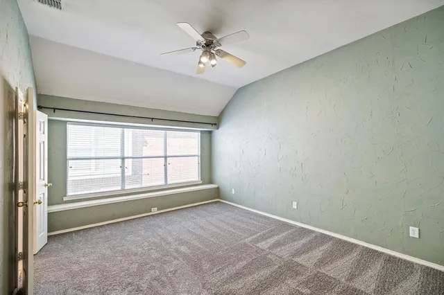 an empty room with chandelier fan and windows