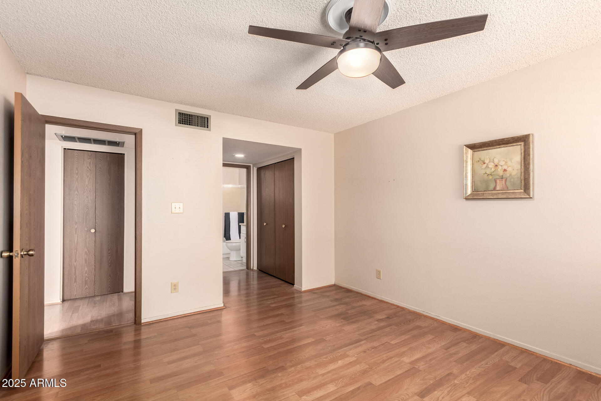 131 North Higley Road, Unit 1 Mesa, AZ 85205 - Photo 13 of 32 an empty room with wooden floor ceiling fan and windows