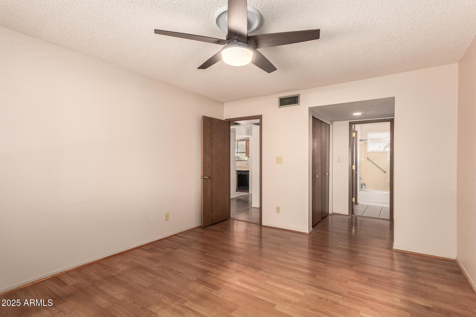 131 North Higley Road, Unit 1 Mesa, AZ 85205 - Photo 17 of 32 an empty room with wooden floor ceiling fan and windows