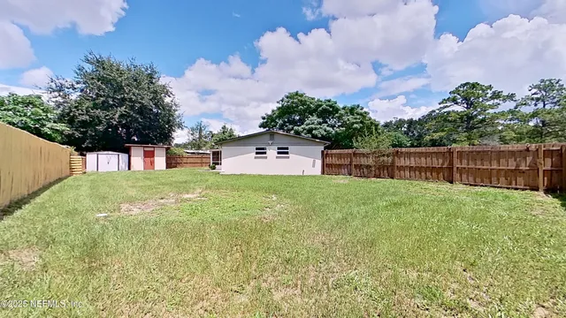 a backyard of a house with plants and barbeque oven