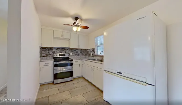 a kitchen with cabinets appliances and a ceiling fan