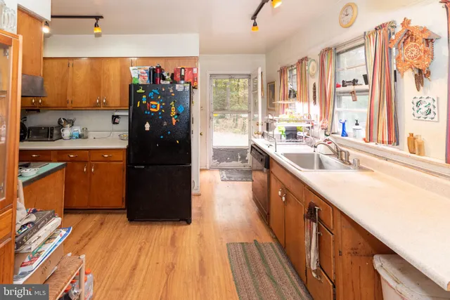 a kitchen with stainless steel appliances granite countertop a refrigerator a sink dishwasher a stove and white countertops with wooden floor