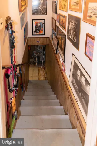 a view of staircase with lots of frames on wall and a chandelier