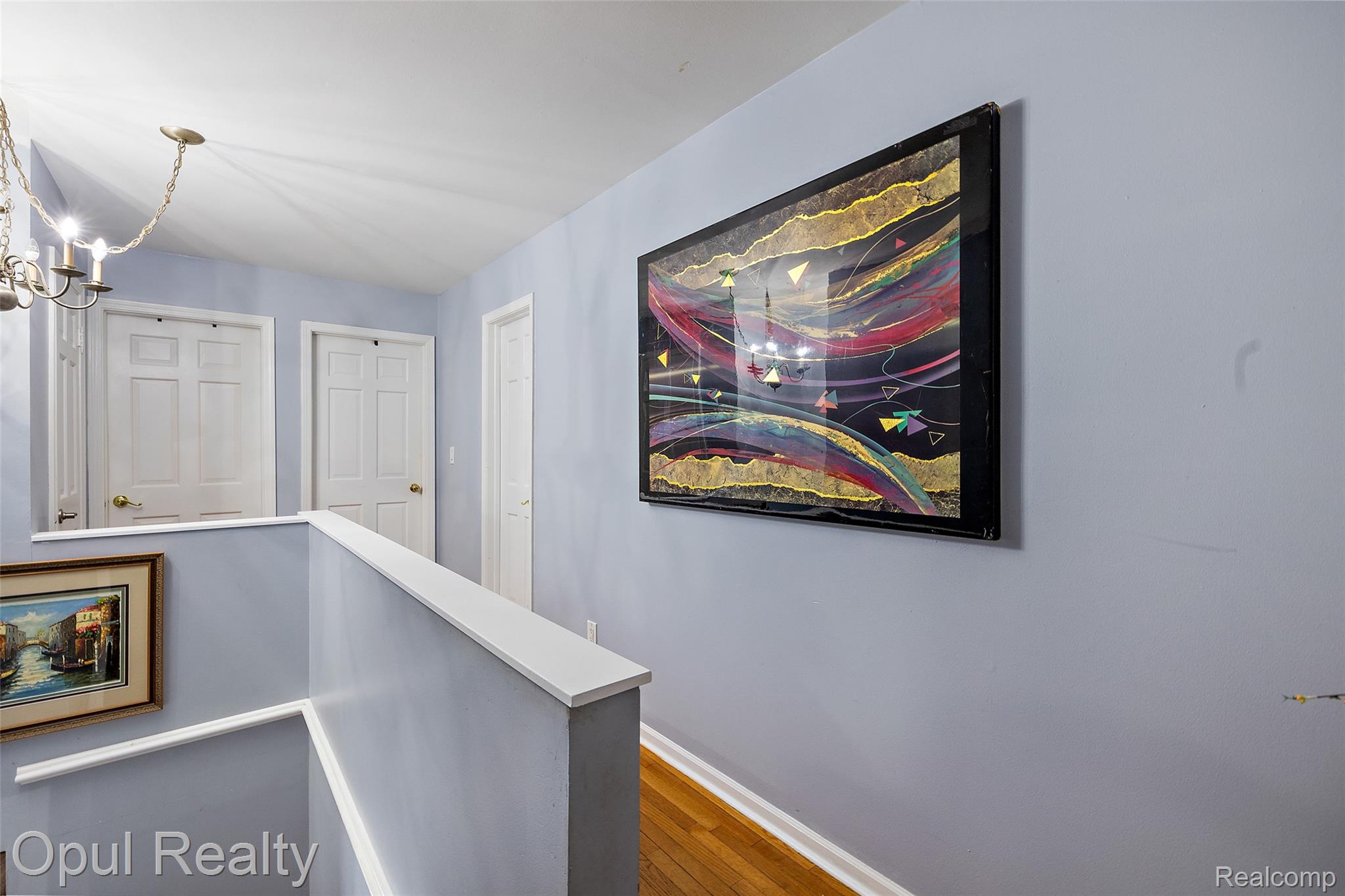 8855 Gross Road Dexter, MI 48130 - Photo 32 of 45 Upper-level hallway featuring wood-finish flooring, light blue wall paint, white trim, and a brass chandelier
