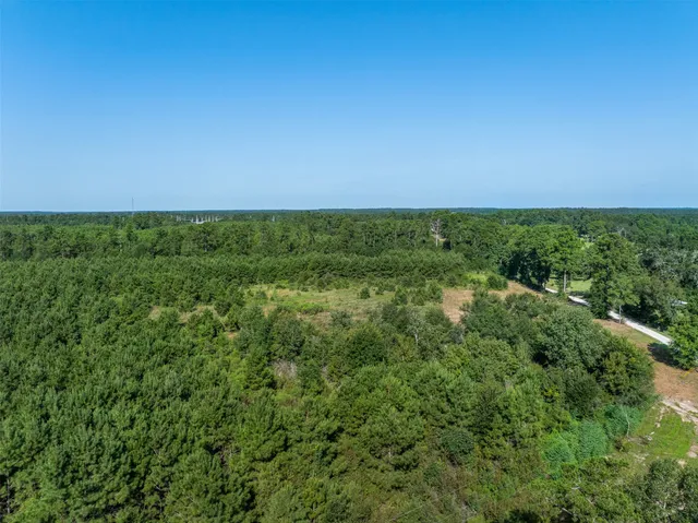 an aerial view of residential house with outdoor space and trees all around