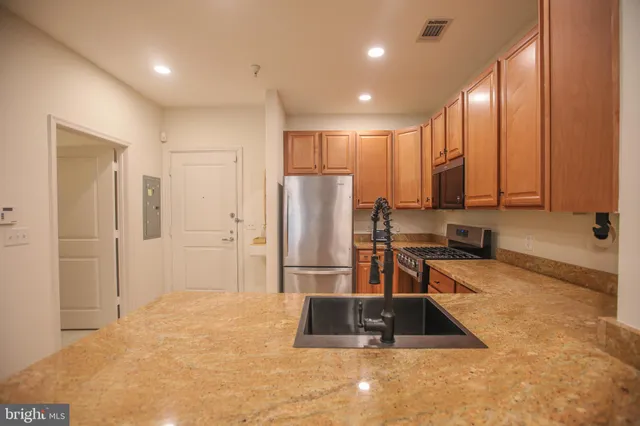 a kitchen with granite countertop a refrigerator and a stove top oven