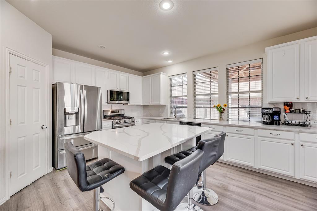 6810 Amesbury Lane Rowlett, TX 75089 - Photo 2 of 22 a large kitchen with kitchen island a large counter top space a sink stainless steel appliances and cabinets