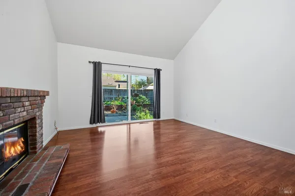 a view of an empty room with wooden floor and a fire place