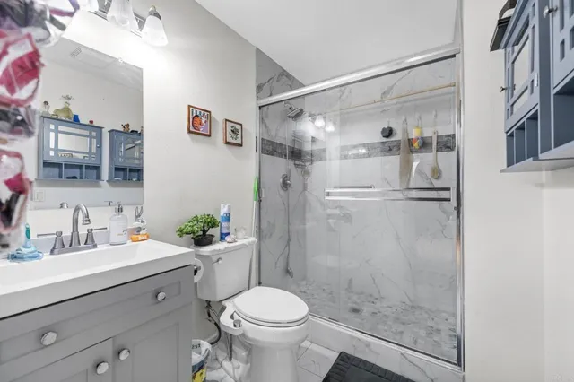 a bathroom with a shower sink vanity mirror and toilet