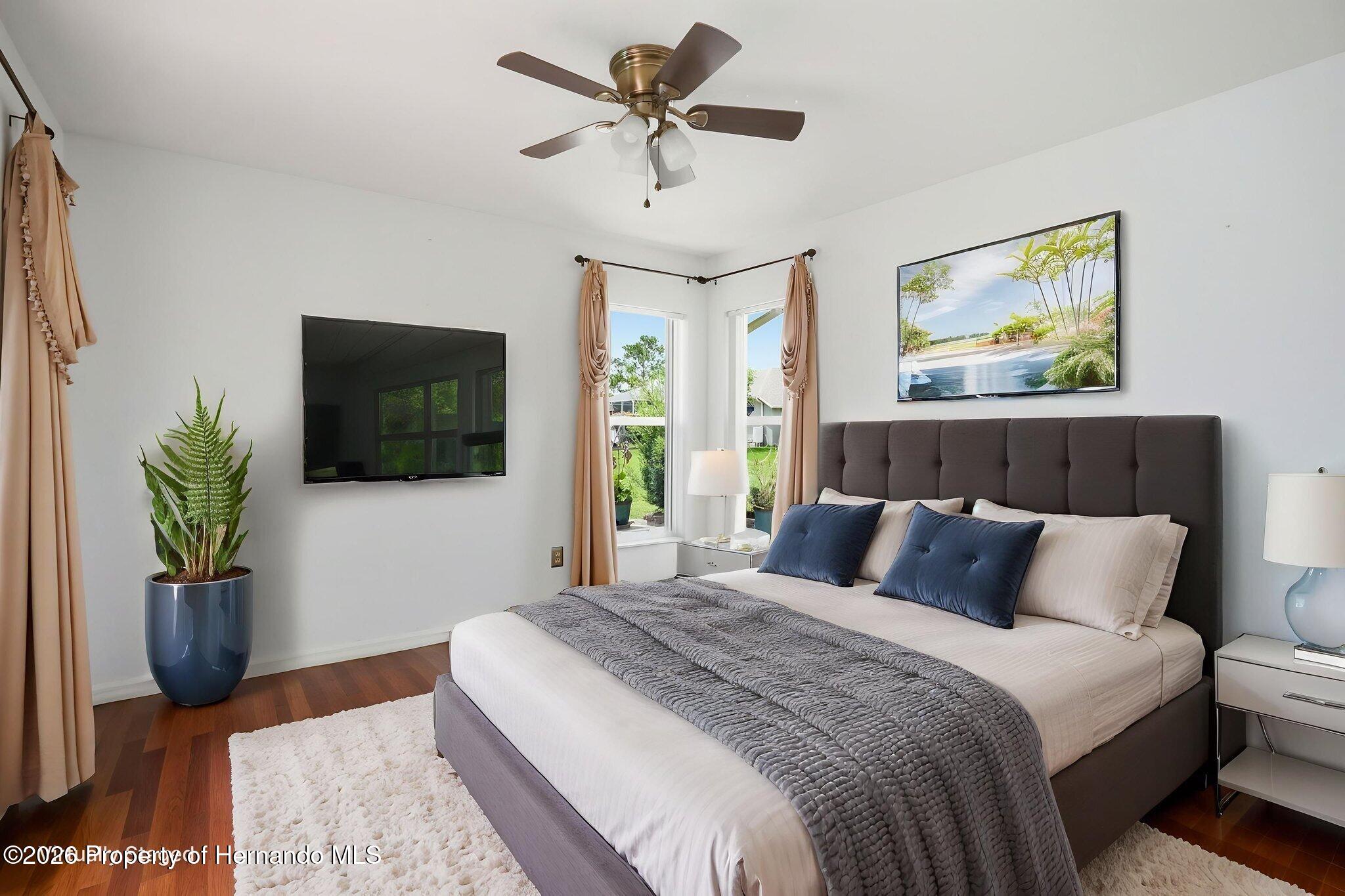 18131 Rivard Boulevard Brooksville, FL 34604 - Photo 39 of 66 a bedroom with a large bed a flat tv screen and a potted plant