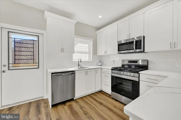 a kitchen with stainless steel appliances white cabinets a sink and a stove