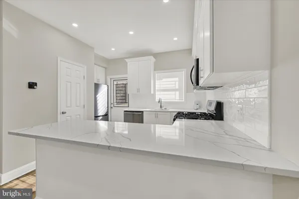 a large white kitchen with kitchen island granite countertop a sink and white cabinets