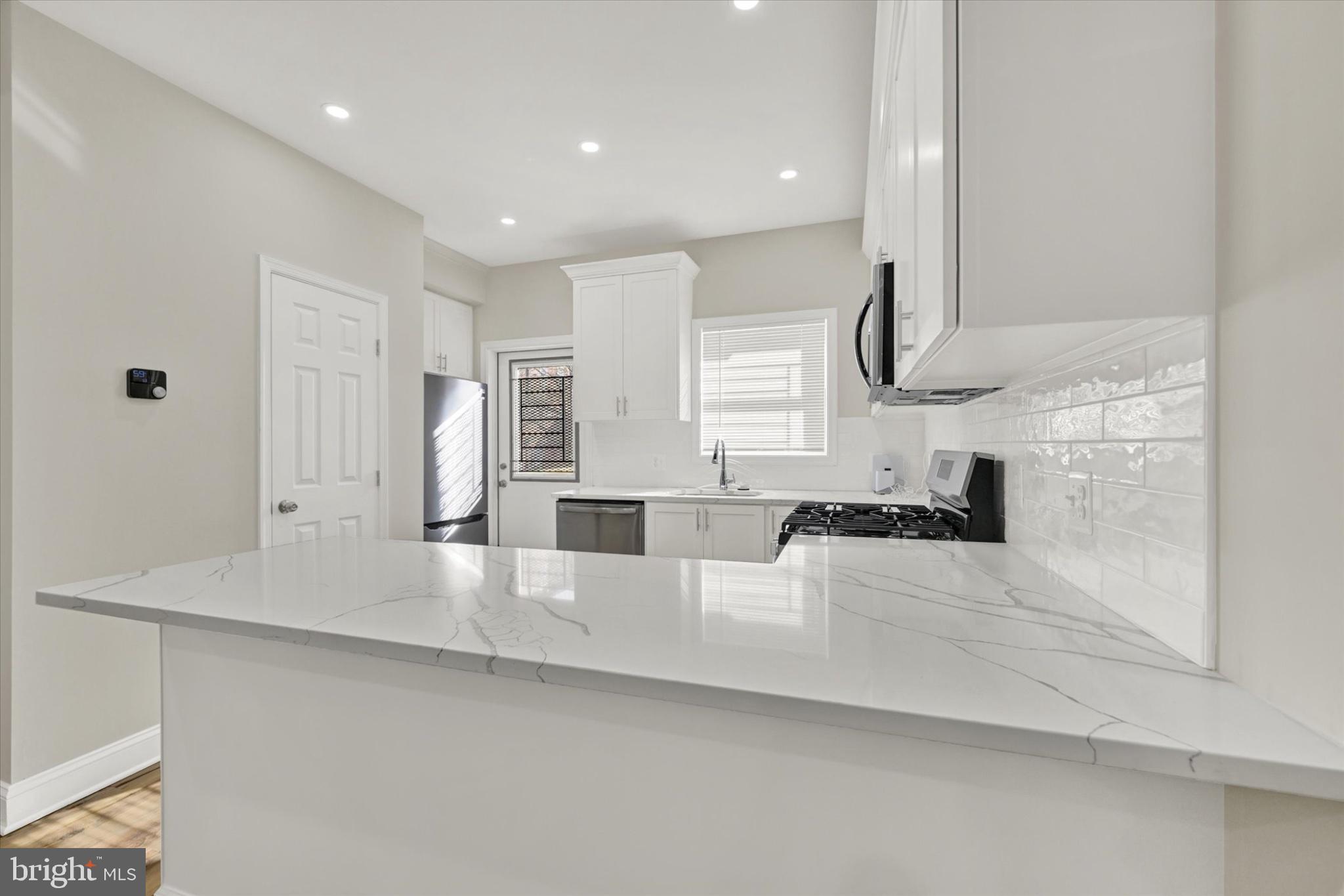 119 North Poppleton Street Baltimore, MD 21201 - Photo 27 of 41 a large white kitchen with kitchen island granite countertop a sink and white cabinets