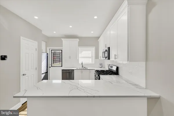 a large white kitchen with sink and refrigerator