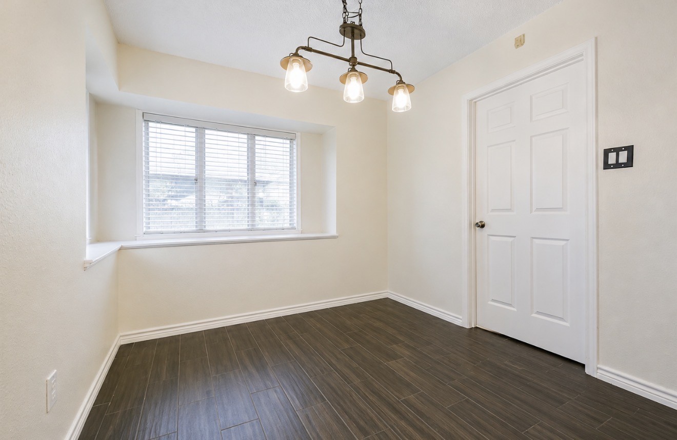 3728 Autumn Lane Baytown, TX 77521 - Photo 10 of 16 Bright, cozy room with warm-toned wood flooring, a large window with blinds, and a stylish three-light fixture. Perfect for a small breakfast area.