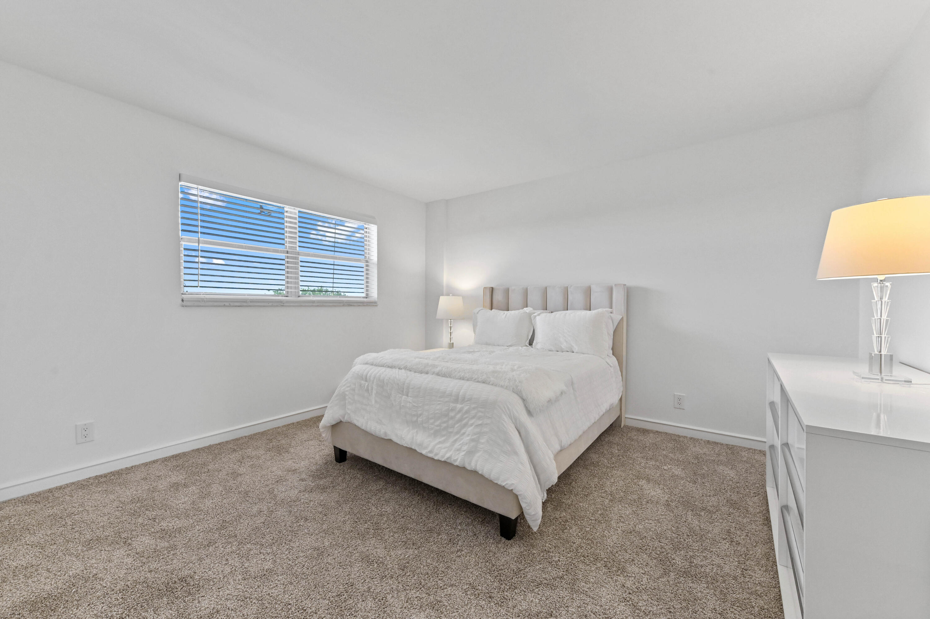 555 Northwest 4th Avenue, Unit 5070 Boca Raton, FL 33432 - Photo 11 of 29 a spacious bedroom with a bed and a lamp on table