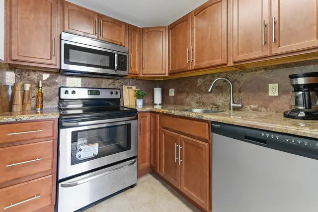 a kitchen with granite countertop wooden cabinets stainless steel appliances and a sink