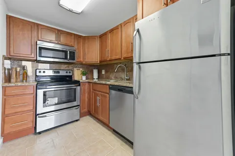 a kitchen with stainless steel appliances granite countertop a refrigerator a stove a sink and a microwave
