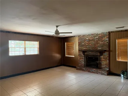an empty room with windows and fireplace