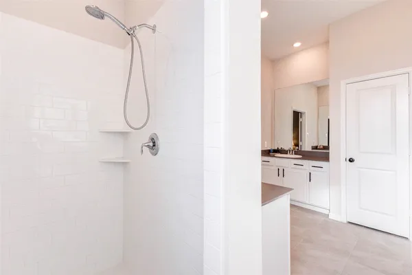 a room with a sink a stove a mirror and a shower
