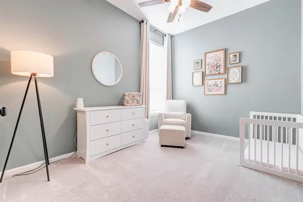 a room with a baby bed a couch and a chandelier