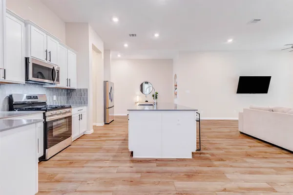 a large kitchen with stainless steel appliances granite countertop a stove a sink and a microwave