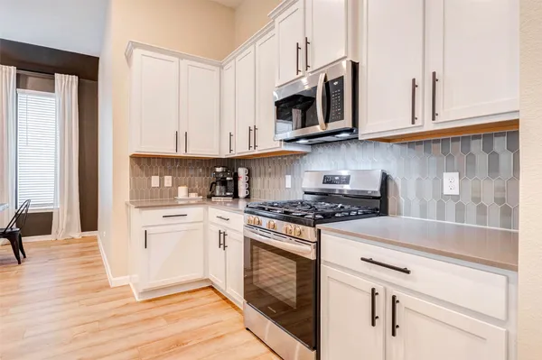 a kitchen with stainless steel appliances granite countertop a stove a microwave and a white cabinets