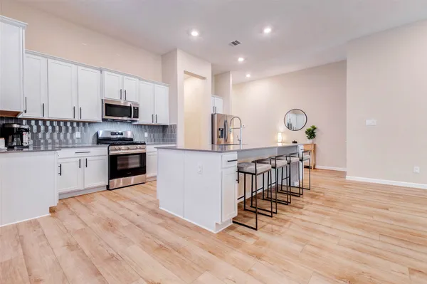 a kitchen with stainless steel appliances kitchen island granite countertop a stove a sink a refrigerator and white cabinets