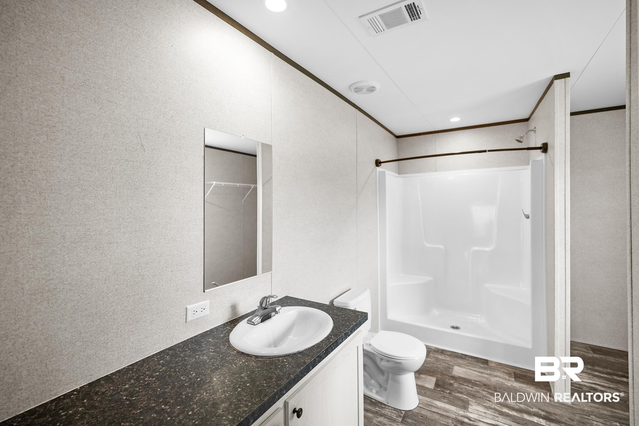 21601 Westside Loop Silverhill, AL 36576 - Photo 25 of 42 Bathroom featuring a single-sink vanity with a dark speckled countertop, white cabinetry, and a rectangular mirror