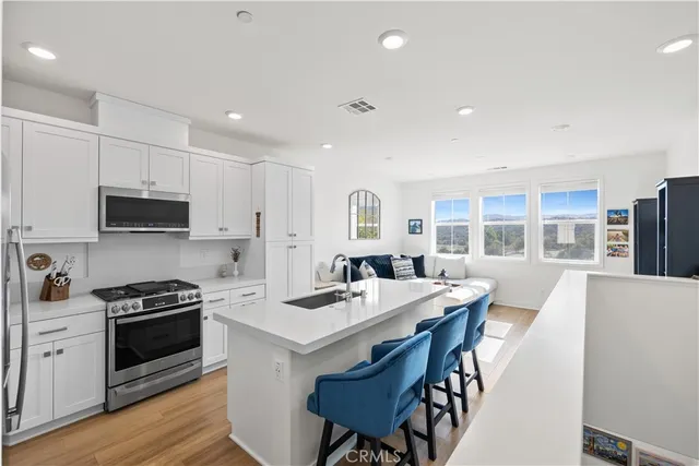 a kitchen with stainless steel appliances kitchen island granite countertop a stove a sink a microwave and a refrigerator