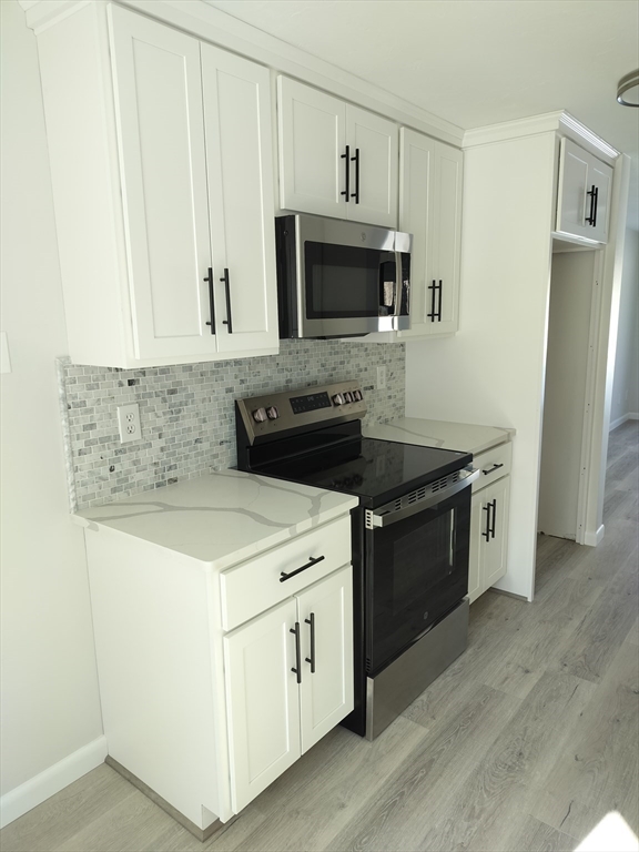 75 Warren Street West, Unit 16 Raynham, MA 02767 - Photo 4 of 22 a kitchen with a stove and a microwave