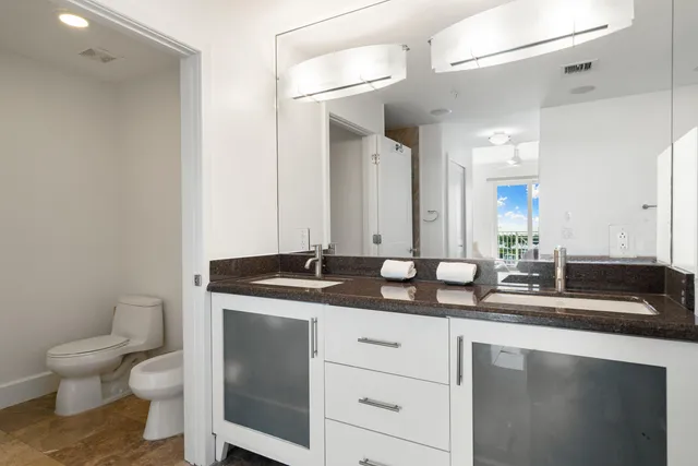 a bathroom with a granite countertop sink a toilet and a mirror