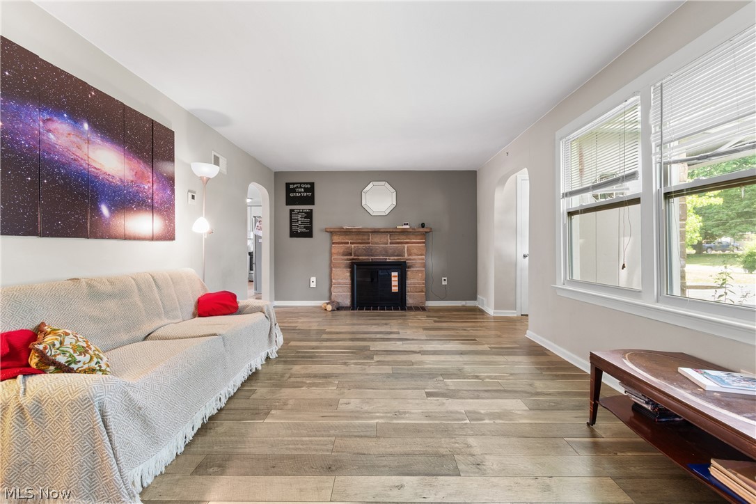 5768 Nolley Road Akron, OH 44319 - Photo 5 of 38 Living area featuring wood-finish flooring, a brick fireplace with hearth, and arched doorways