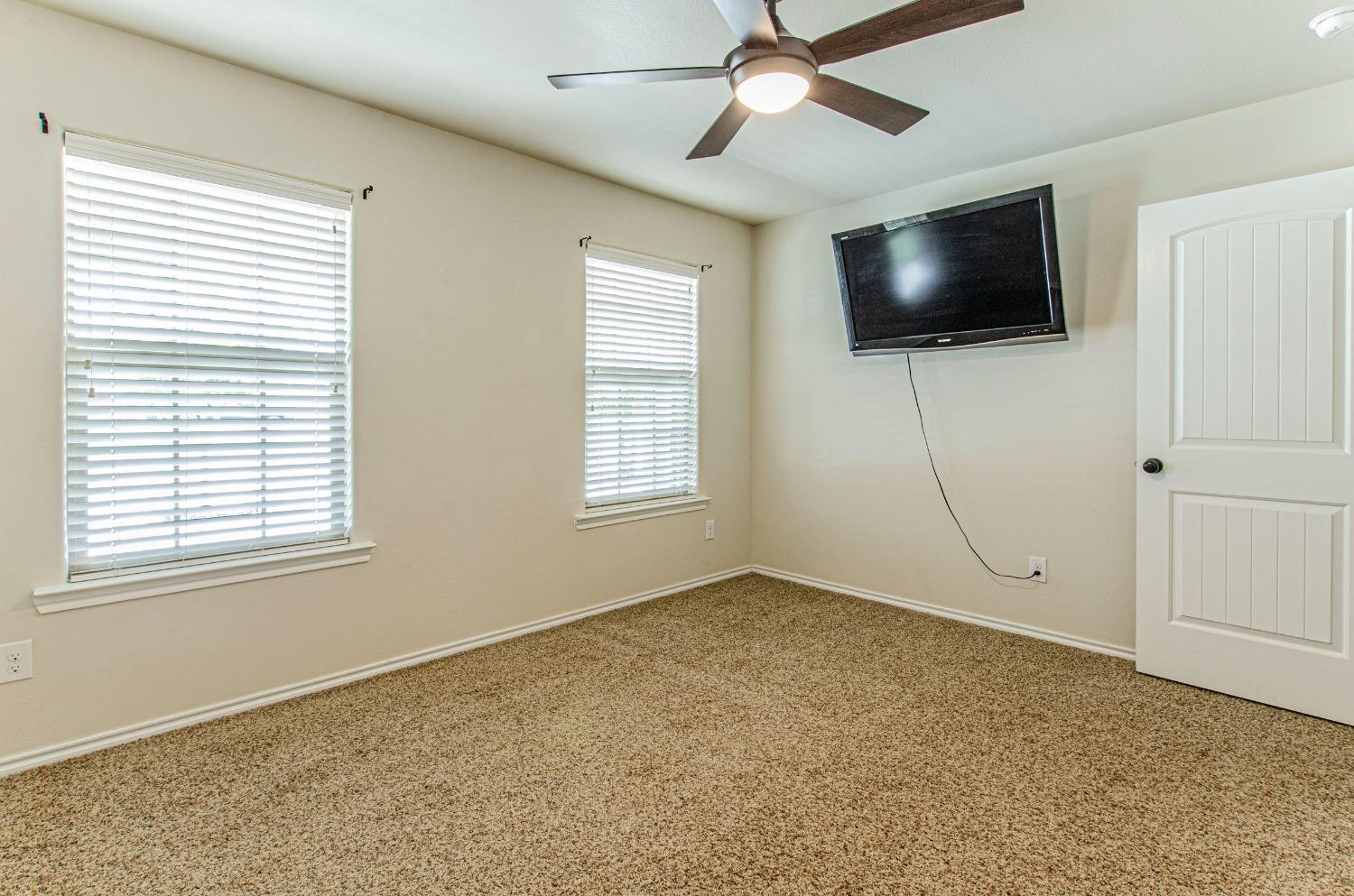 9105 Rochester Avenue Lubbock, TX 79424 - Photo 11 of 24 en empty room with windows and flat screen tv