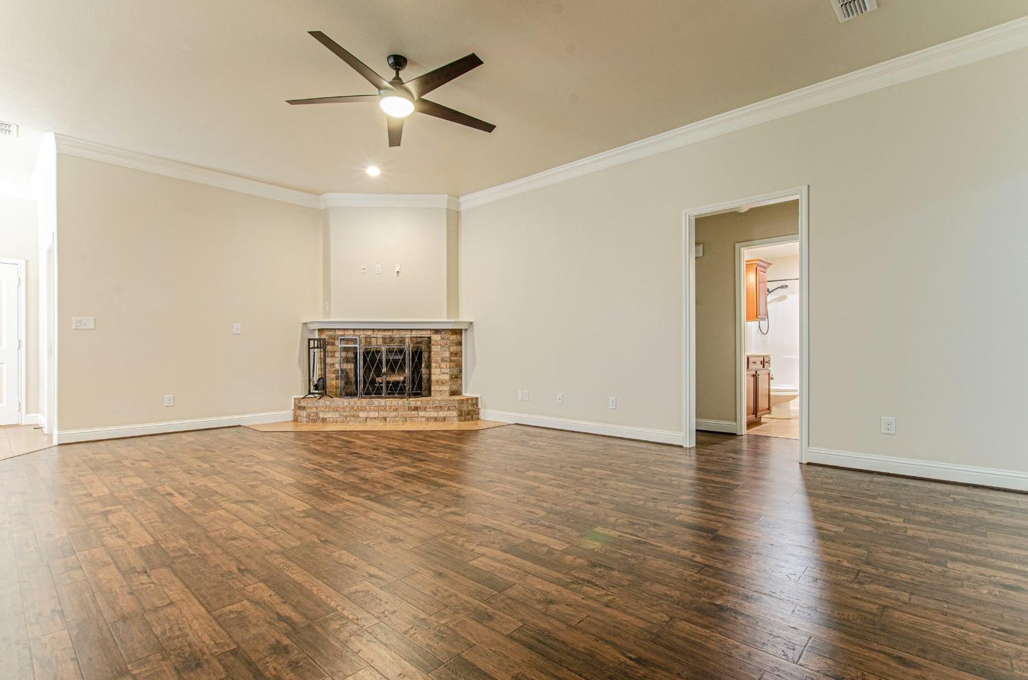 9105 Rochester Avenue Lubbock, TX 79424 - Photo 21 of 24 a view of an empty room with wooden floor and a ceiling fan