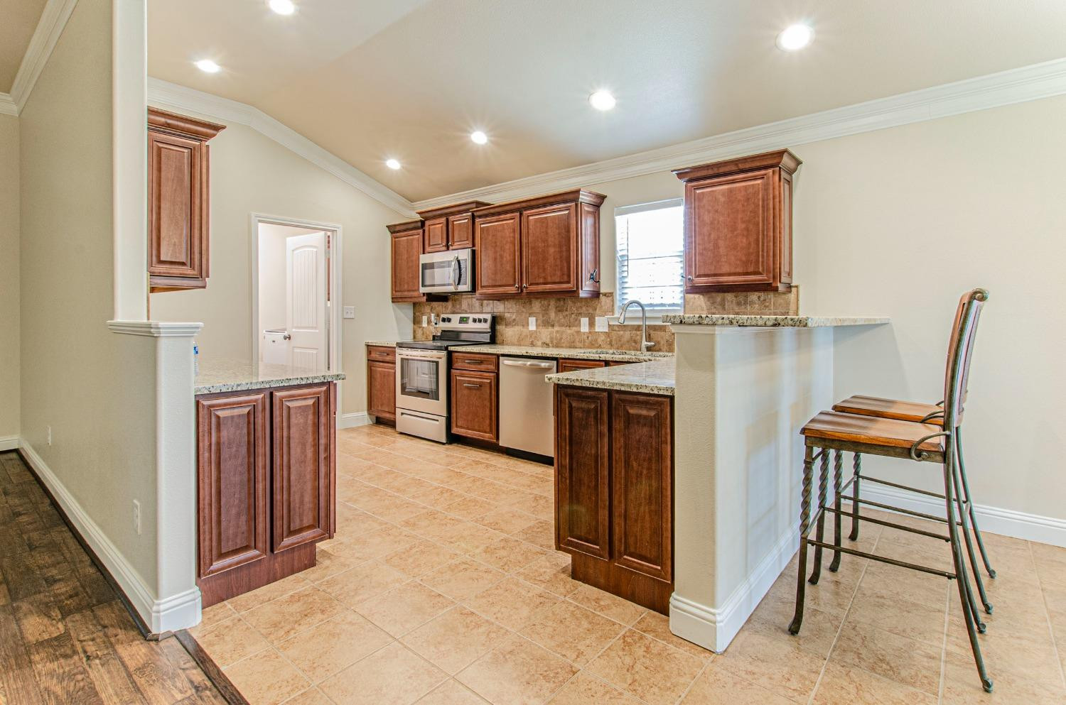 9105 Rochester Avenue Lubbock, TX 79424 - Photo 22 of 24 a kitchen with stainless steel appliances granite countertop a stove top oven a sink and a refrigerator