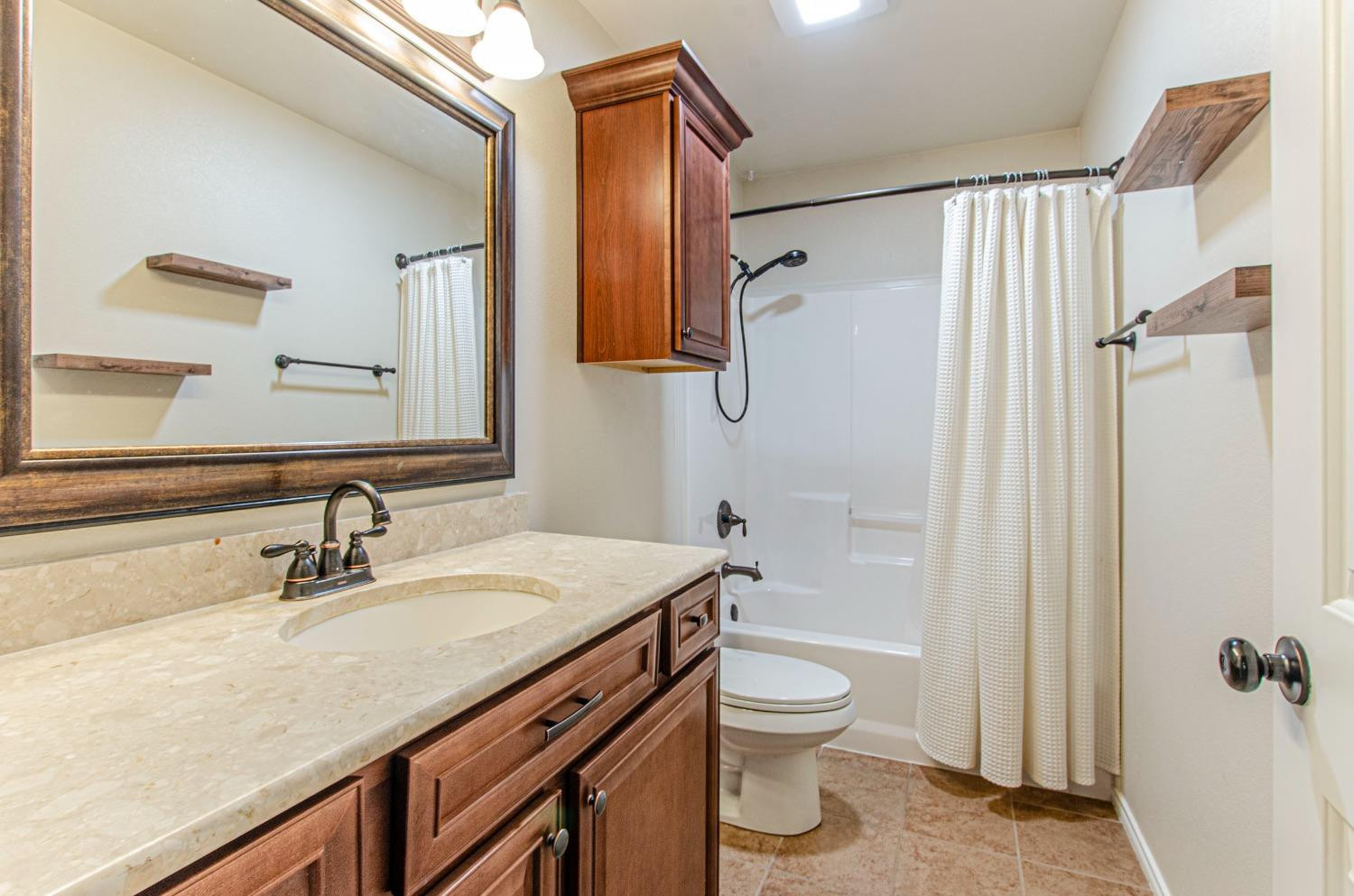 9105 Rochester Avenue Lubbock, TX 79424 - Photo 9 of 24 a bathroom with a granite countertop sink toilet and shower