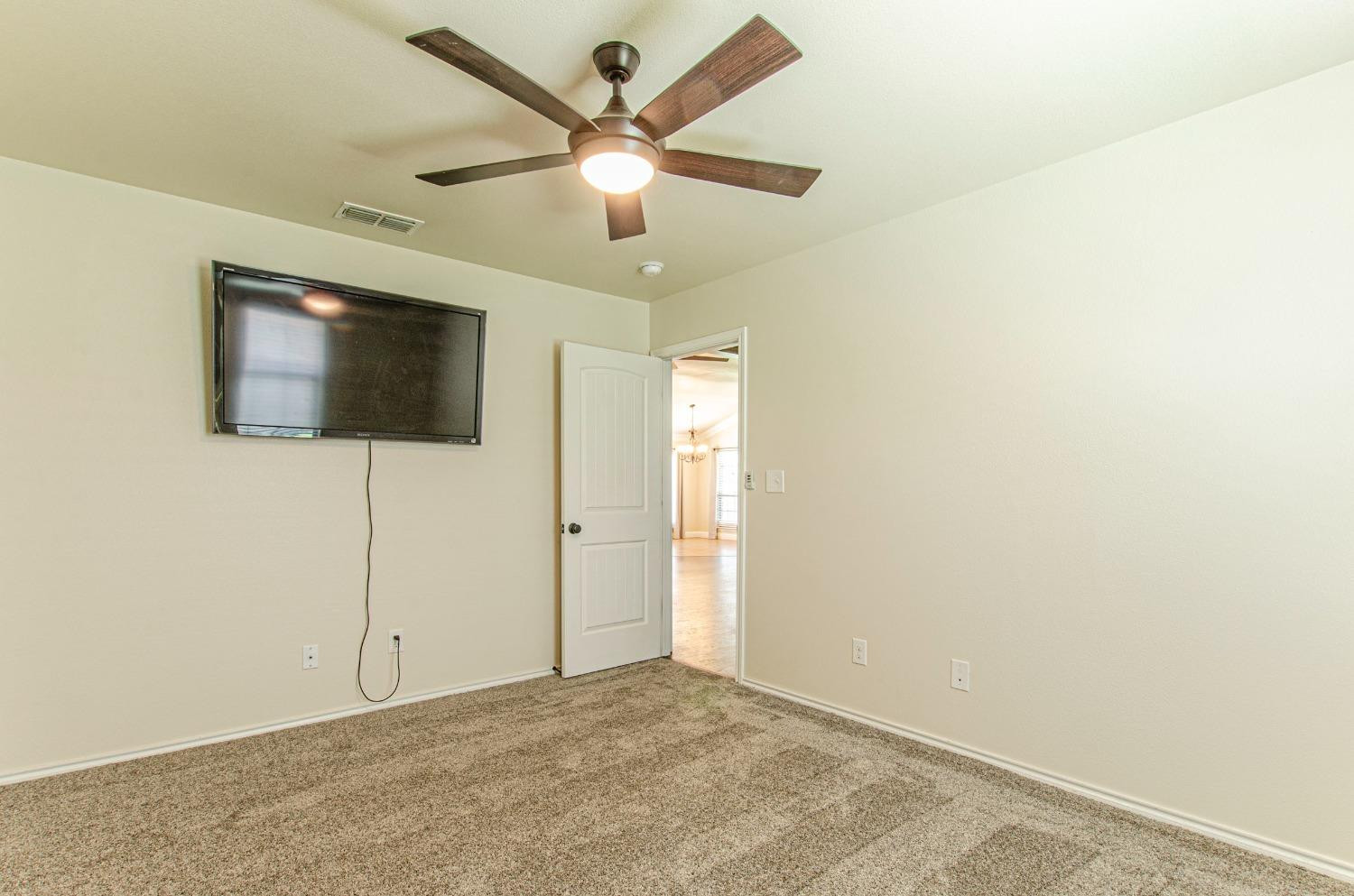 9105 Rochester Avenue Lubbock, TX 79424 - Photo 10 of 24 en empty room with a flat screen tv and ceiling fan