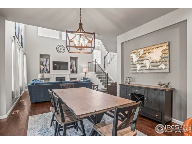 a dining room with wooden floor a chandelier a wooden table and chairs