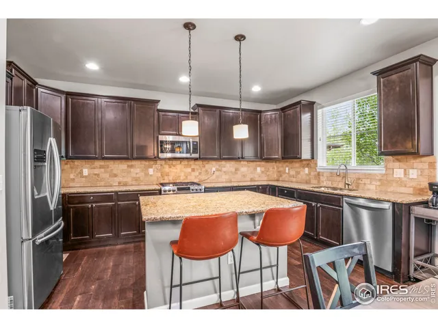 a kitchen with stainless steel appliances kitchen island a table chairs in it and wooden floors