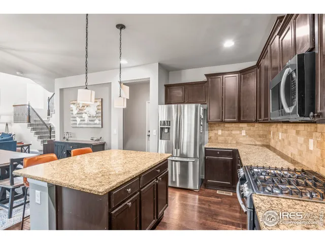 a kitchen with stainless steel appliances kitchen island granite countertop a refrigerator a stove and a sink