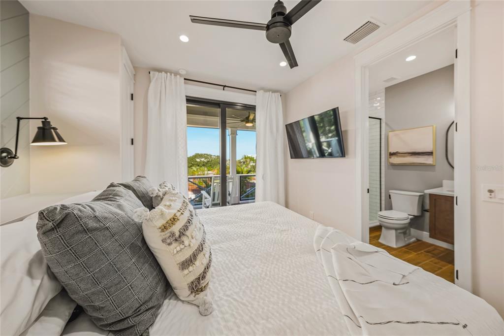 6910 Midnight Pass Road, Unit A Sarasota, FL 34242 - Photo 17 of 40 a bedroom with a large bed and a flat screen tv