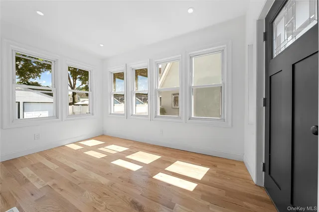 a view of an empty room with window and wooden floor