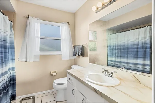 a bathroom with a granite countertop sink toilet and mirror