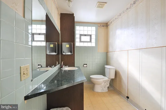 a bathroom with a granite countertop sink a toilet a mirror and shower