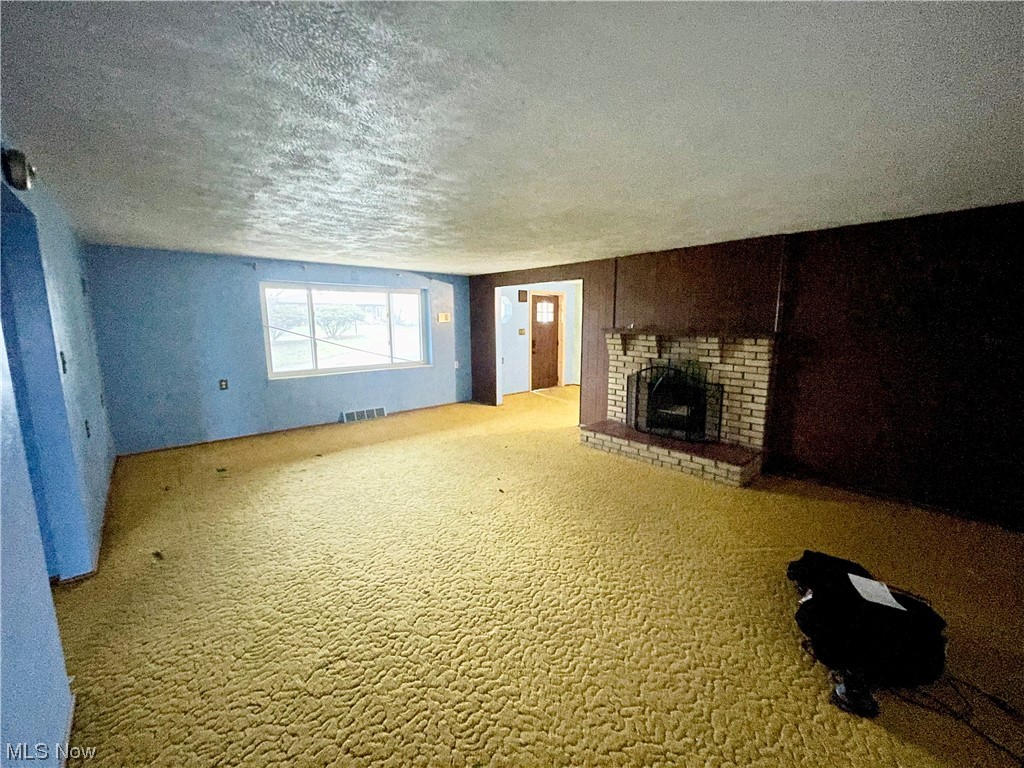 120 View Road Wellsburg, WV 26070 - Photo 8 of 27 Unfurnished living room featuring light carpet, a textured ceiling, and a brick fireplace