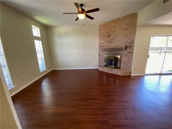an empty room with wooden floor fireplace and windows
