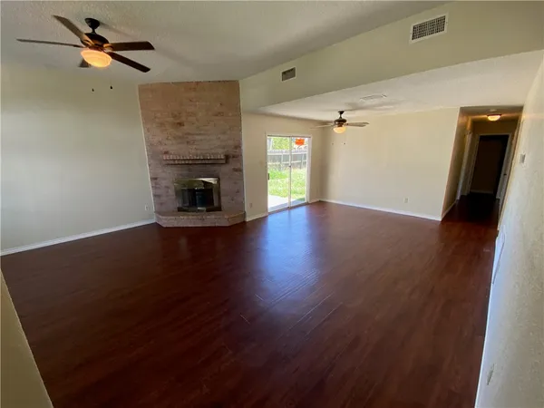 an empty room with wooden floor fireplace and windows