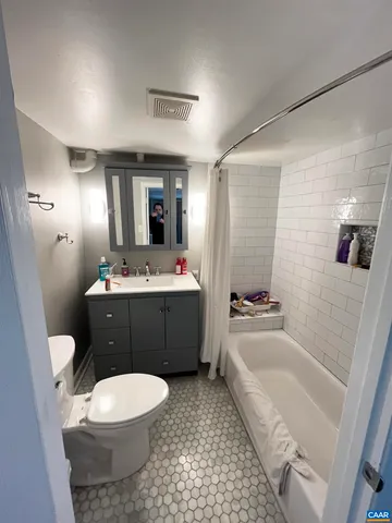 a bathroom with a bathtub shower sink vanity mirror and toilet
