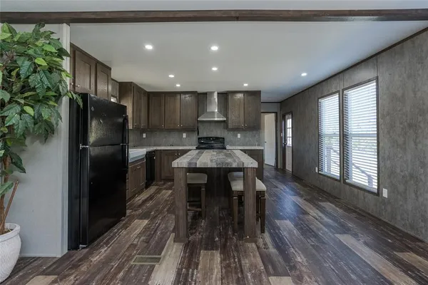 a kitchen with stainless steel appliances granite countertop a refrigerator a stove a sink dishwasher and a dining table with wooden floor